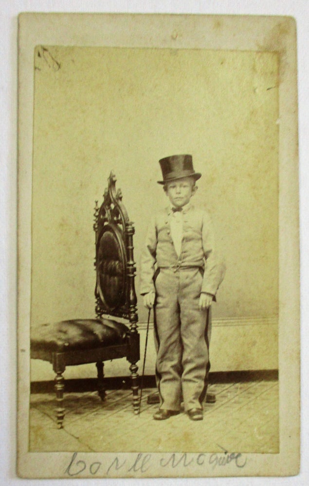 Item #36453 CARTE DE VISITE OF UNKNOWN YOUNG DWARF, POSSIBLY A PERFORMER, STANDING NEXT TO AN ORNATE CHAIR WHILE WEARING A SUIT AND TOP HAT AND HOLDING A CANE IN HIS HAND. Unknown Dwarf.